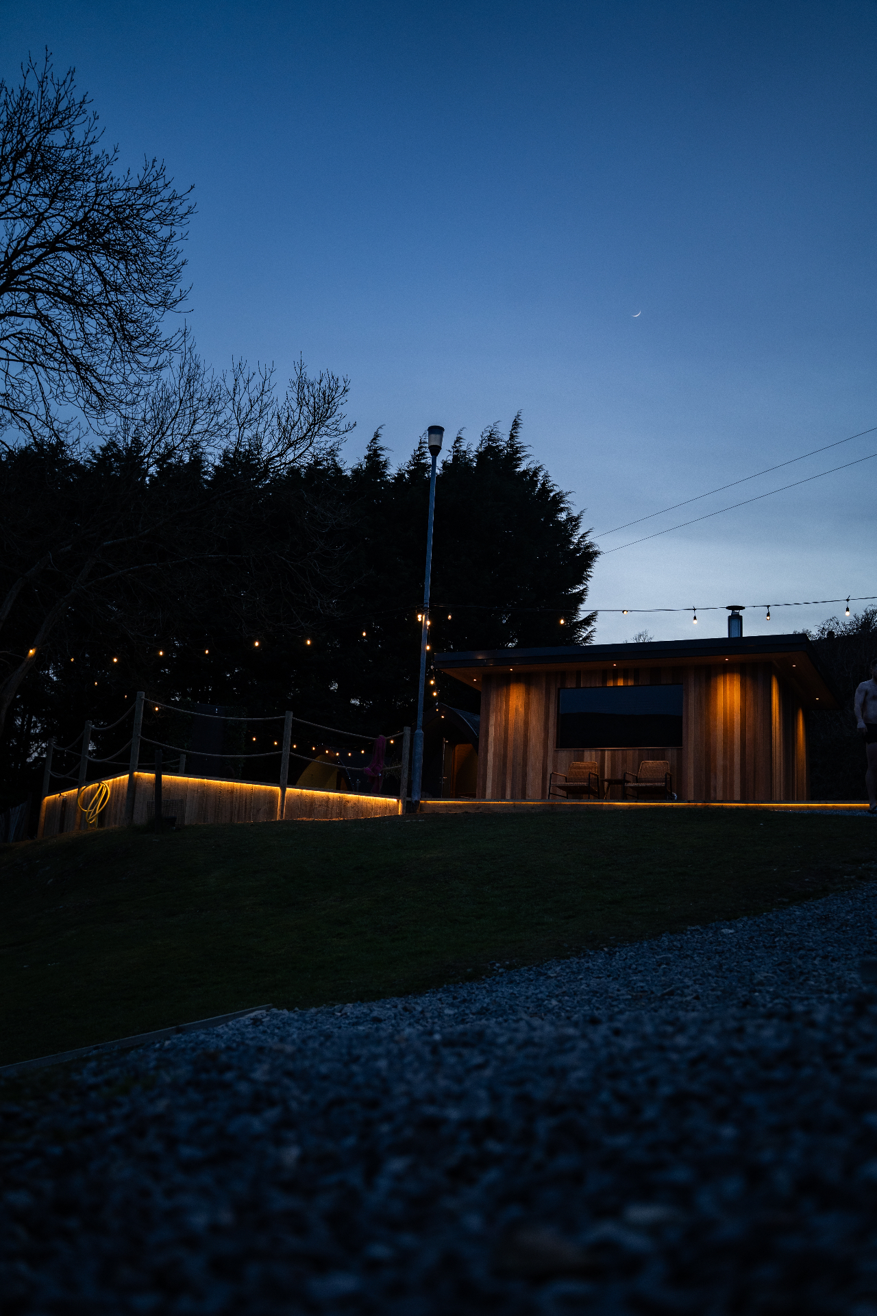 Wood-clad sauna glowing at dusk with string lights